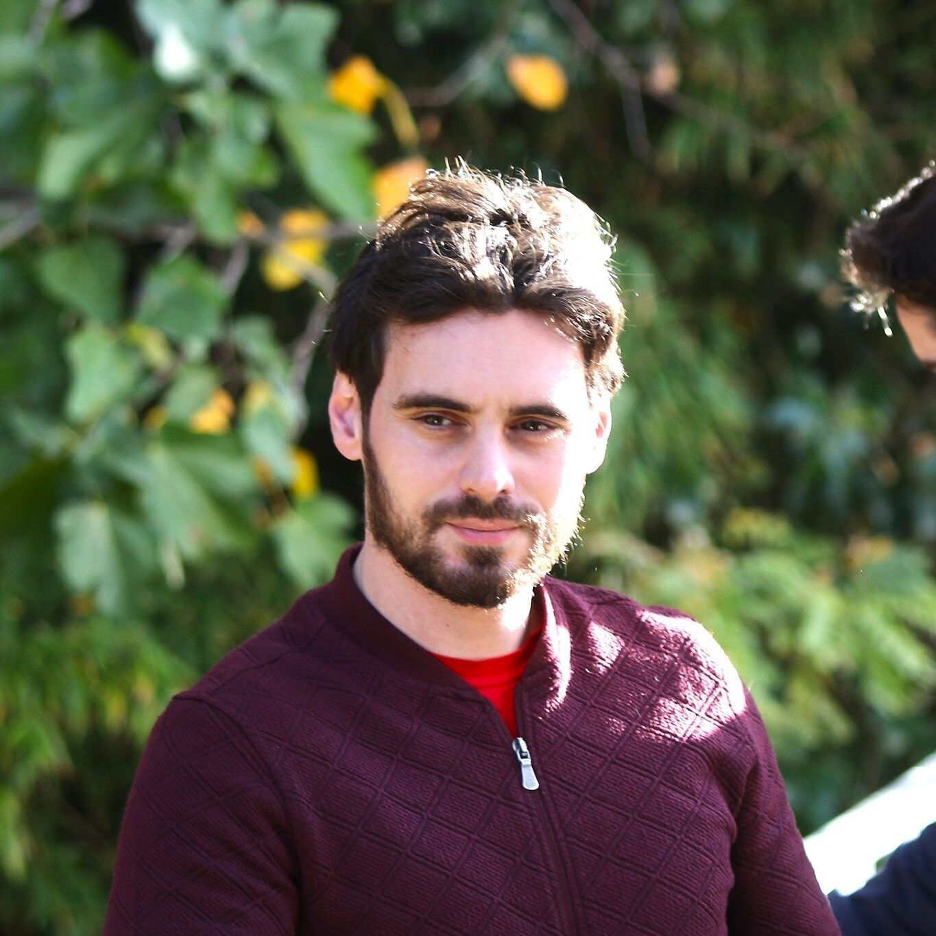 Portrait de Gabriel Tardio, encadrant du club, en extérieur devant un feuillage.